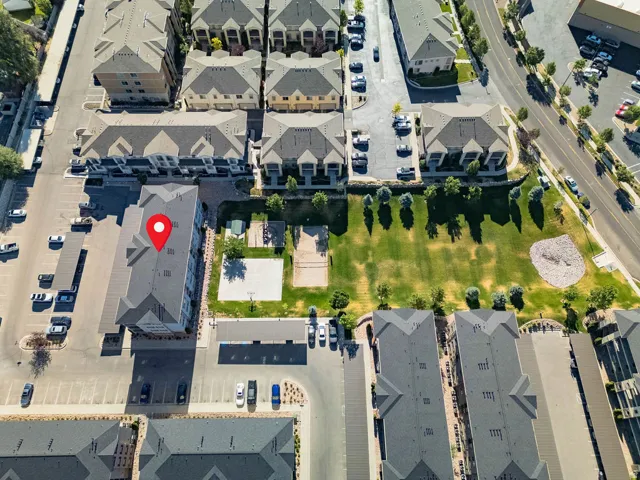 Aerial perspective showcasing a multi-story residential building with gabled roofs, surrounded by paved parking areas