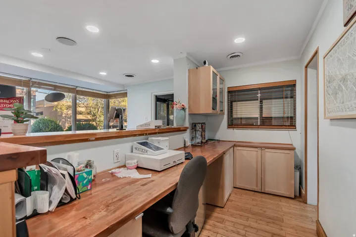 Integrated reception desk with wood-finish countertop, recessed lighting, and ample natural light from extensive window frontage