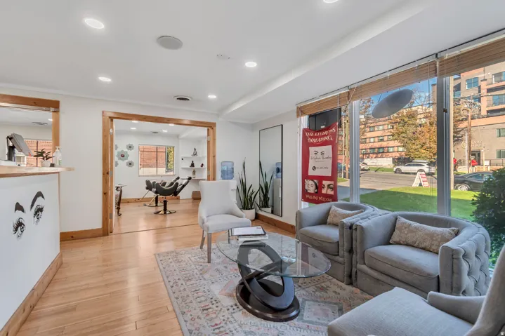 Spacious commercial interior featuring large storefront windows, recessed lighting, wood-finish flooring, and natural wood trim accents