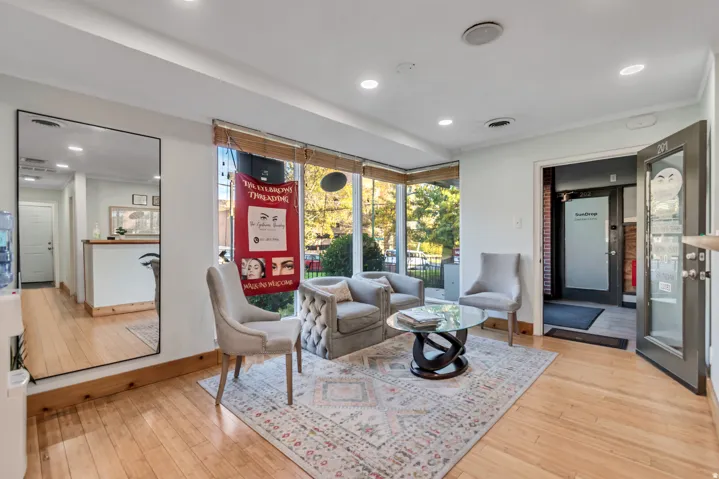Spacious reception area featuring wood-finish flooring, recessed lighting, and large windows with natural light