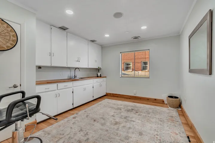 Expansive white cabinetry with wood-finish countertops and integrated sink