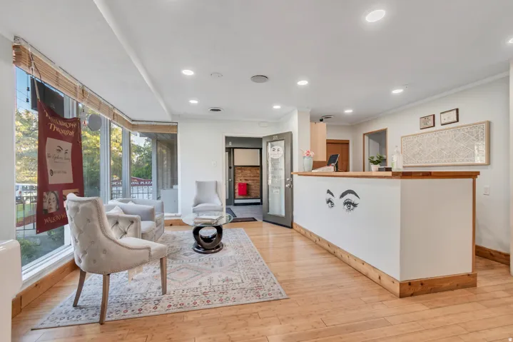 Reception area featuring wood-finish flooring, a wood-trimmed counter, recessed lighting, expansive bay windows, and a glass-paneled door