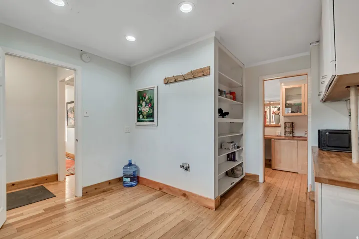 Hardwood flooring extends throughout this space, featuring recessed lighting and built-in shelving
