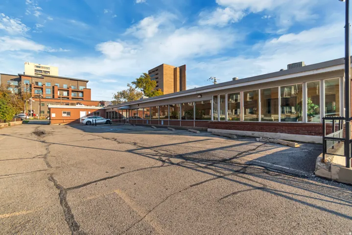 Expansive asphalt parking area fronting a brick and glass-fronted commercial building