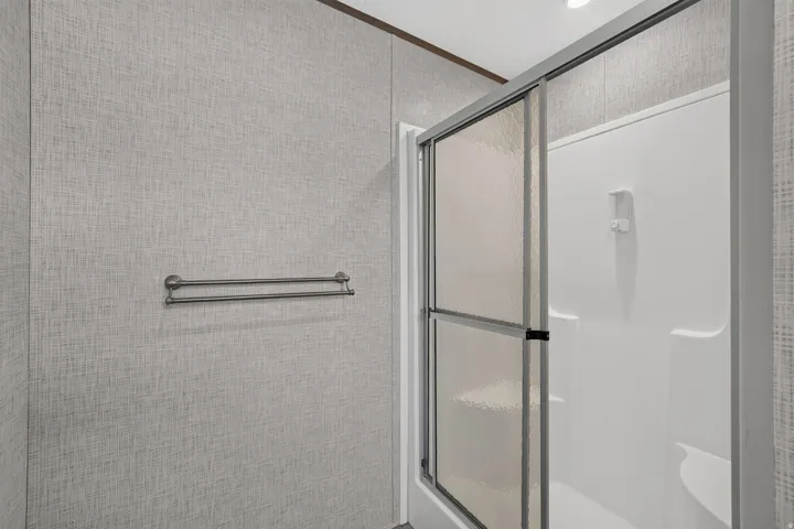 Walk-in shower with sliding textured glass doors and integrated shelving
