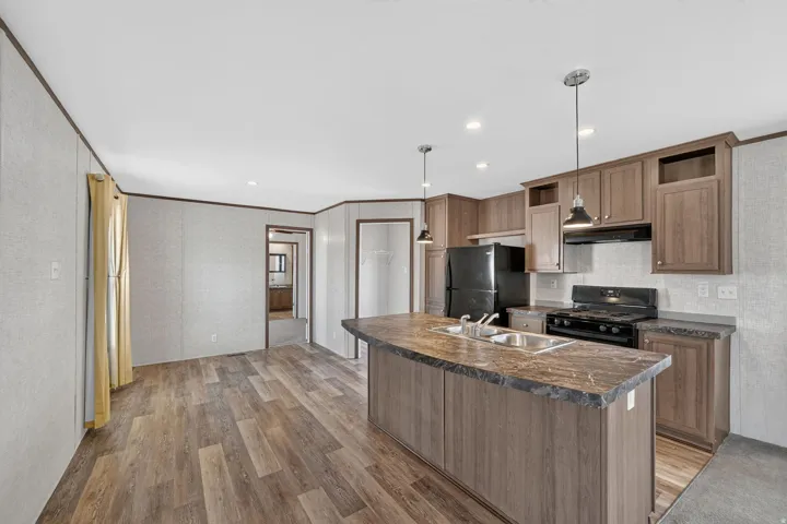 Kitchen featuring a gas range, black appliances, and pendant lighting over a center island with an integrated sink