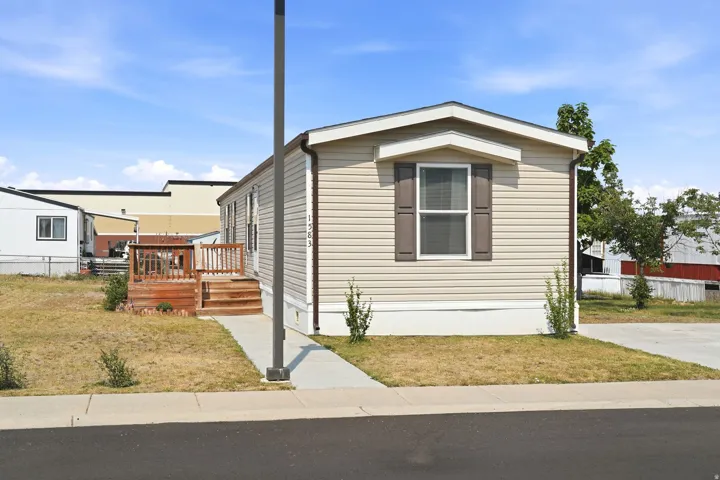 Single-story residence featuring light-colored siding, dark shutters, and a front window