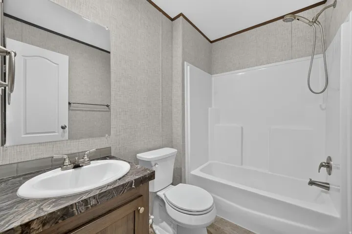 Bathroom featuring a white vanity with an oval sink, dark marbled countertop, brushed nickel faucet, and a large wall mirror