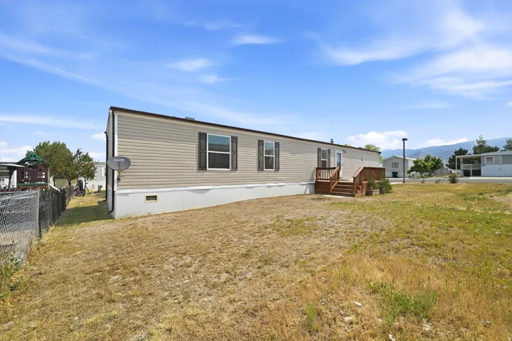 Single-story home featuring tan horizontal siding, dark brown trim, and a white foundation skirt