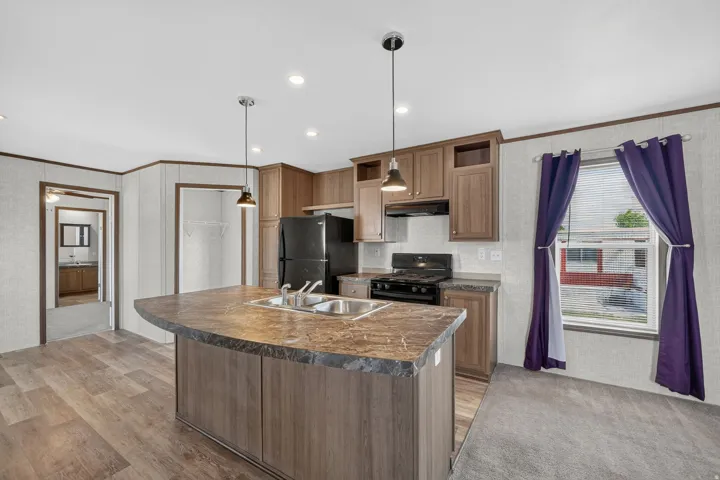 Kitchen island with an integrated double basin sink, dark wood-finish cabinetry, black appliances, recessed lighting, and pendant lighting fixtures
