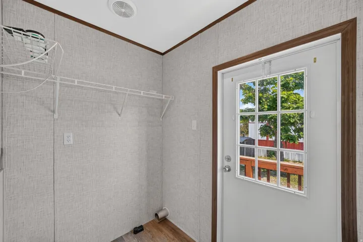 Utility area featuring wood-finish flooring and light-toned wall paneling