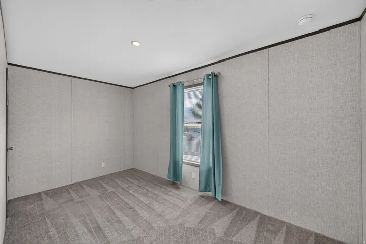Room with patterned carpet, light-colored textured wall panels, a single window, and recessed ceiling lighting