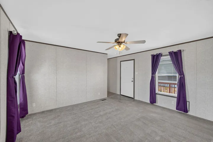 Living area featuring gray carpeting, a white ceiling, and light-colored wall paneling