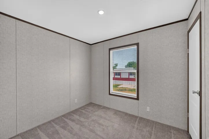 Carpeted room featuring a single window with blinds, a white door, recessed ceiling lighting, and textured wall panels with dark trim