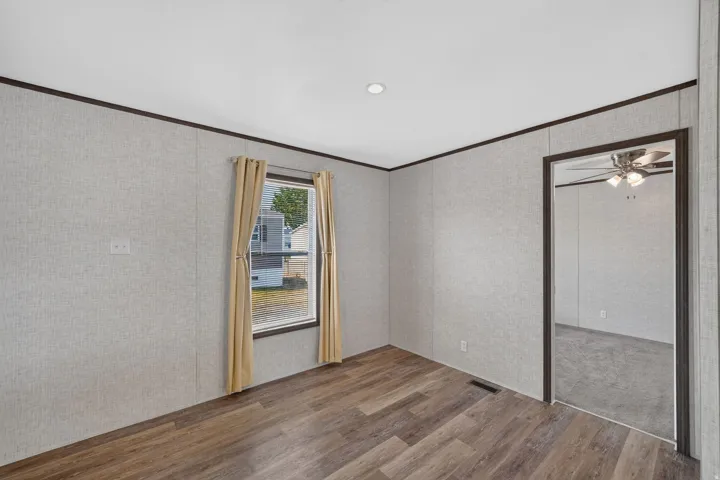 Spacious interior room featuring wood-finish flooring, a window with natural light, and recessed ceiling lighting