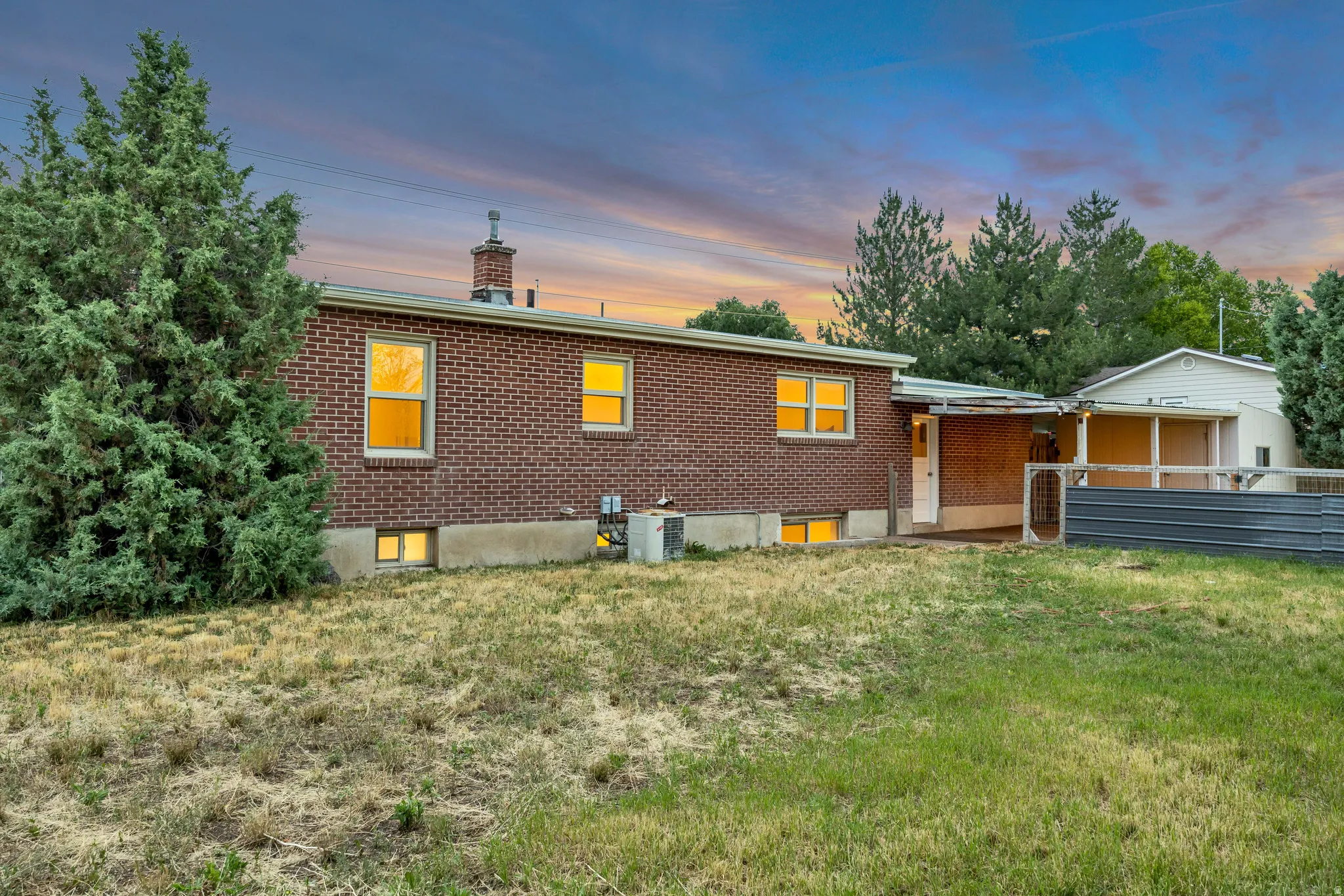 Red brick exterior featuring multiple windows and a covered patio area
