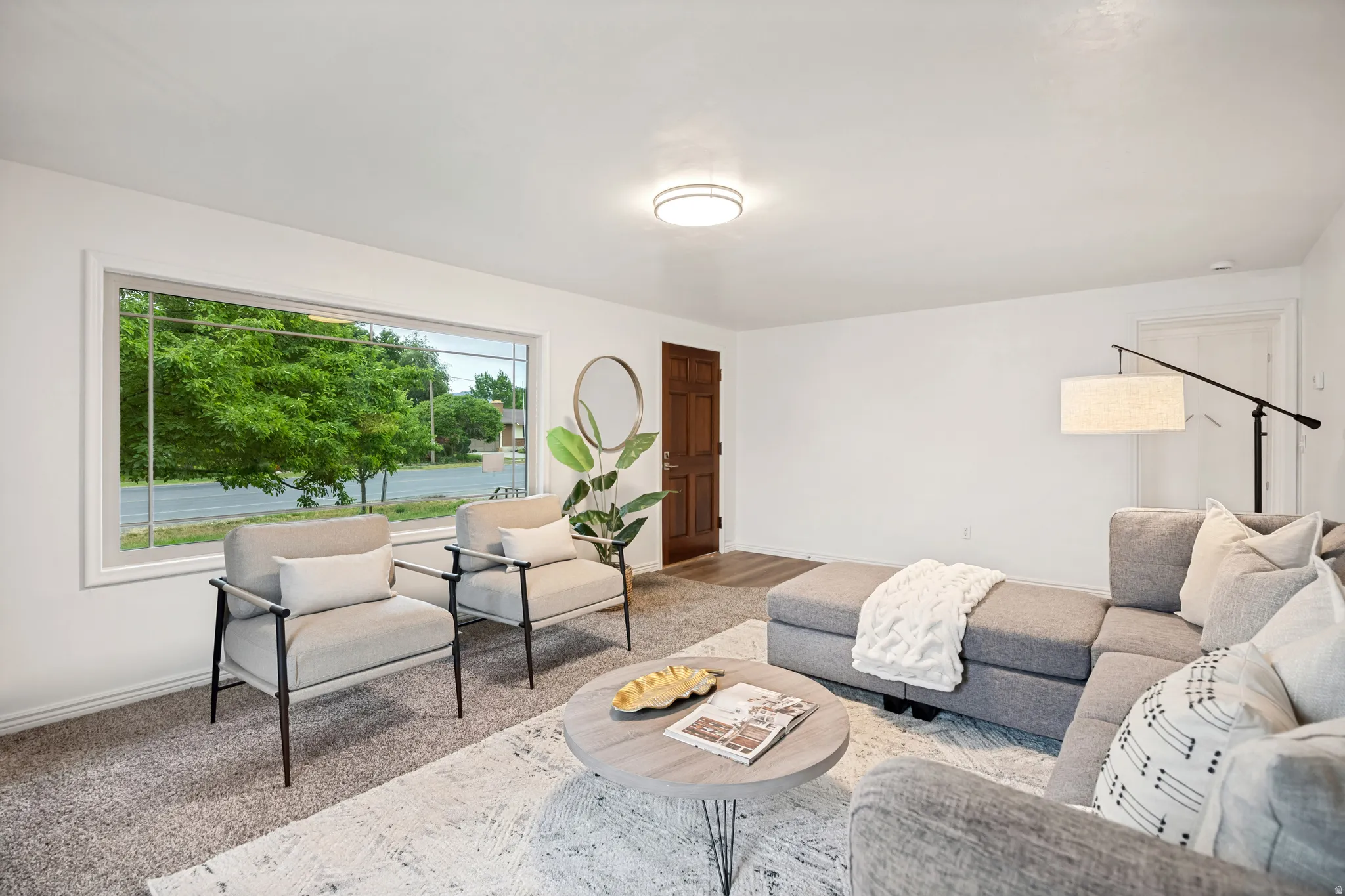 Living area featuring a wide picture window, wall-to-wall carpeting, and a visible wood paneled door