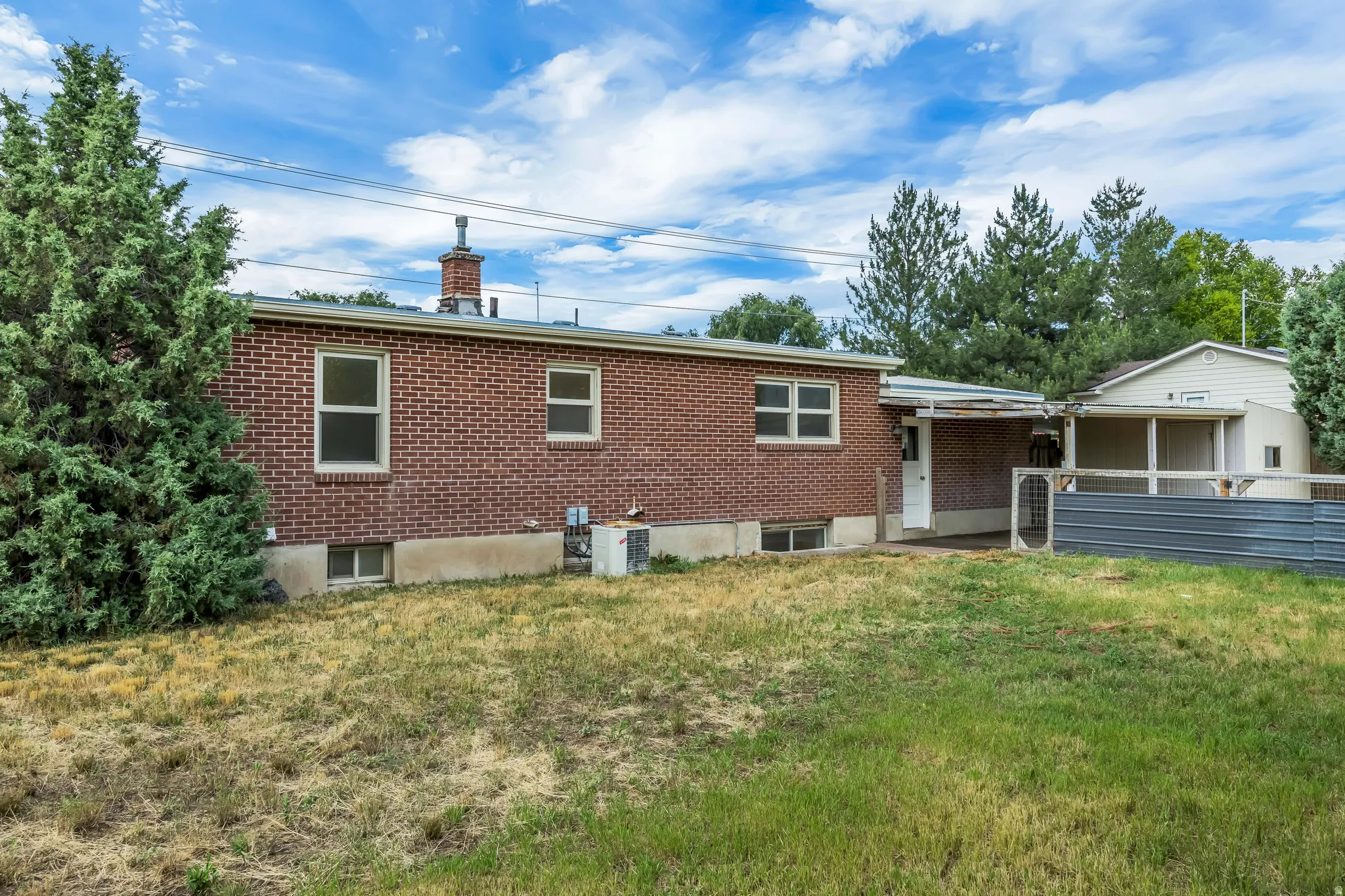 Spacious property featuring a red brick exterior, multiple windows, a covered patio, and a separate structure with an additional covered area