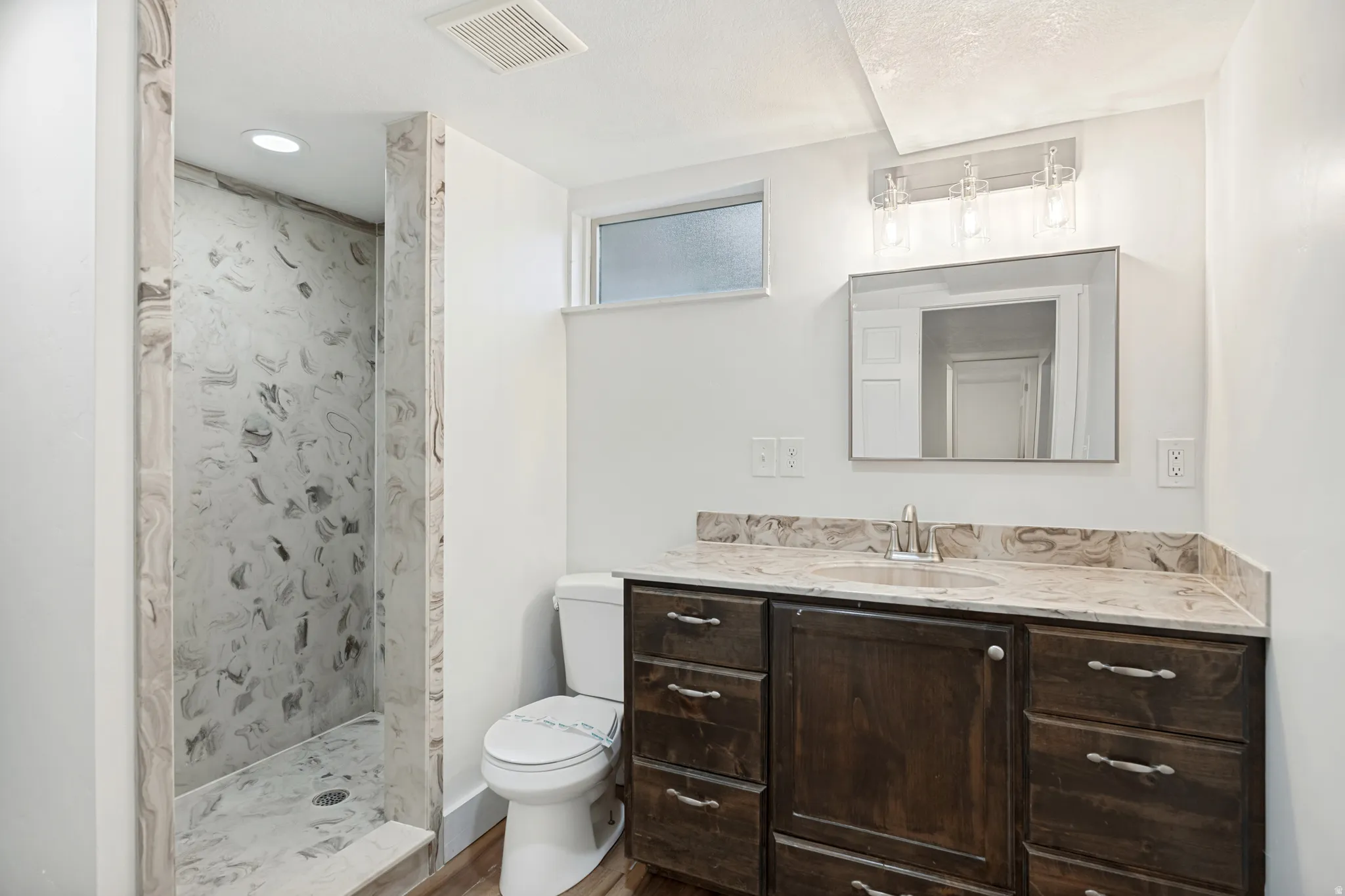 Bathroom featuring a walk-in shower with patterned wall and floor tiles