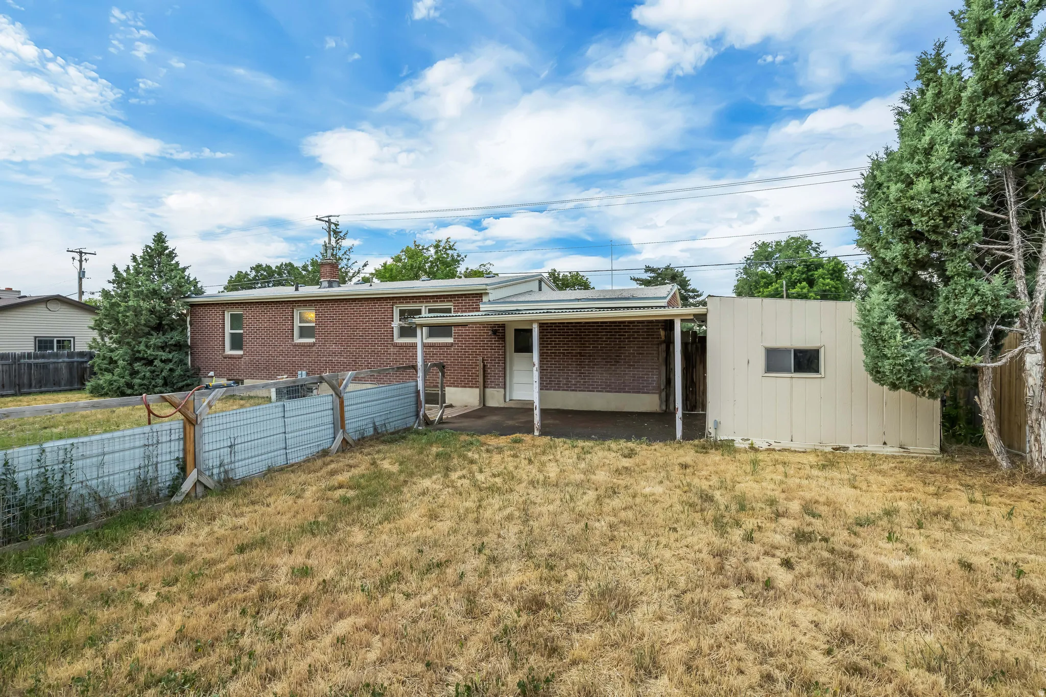 Expansive backyard featuring a brick exterior, covered patio, and a detached shed