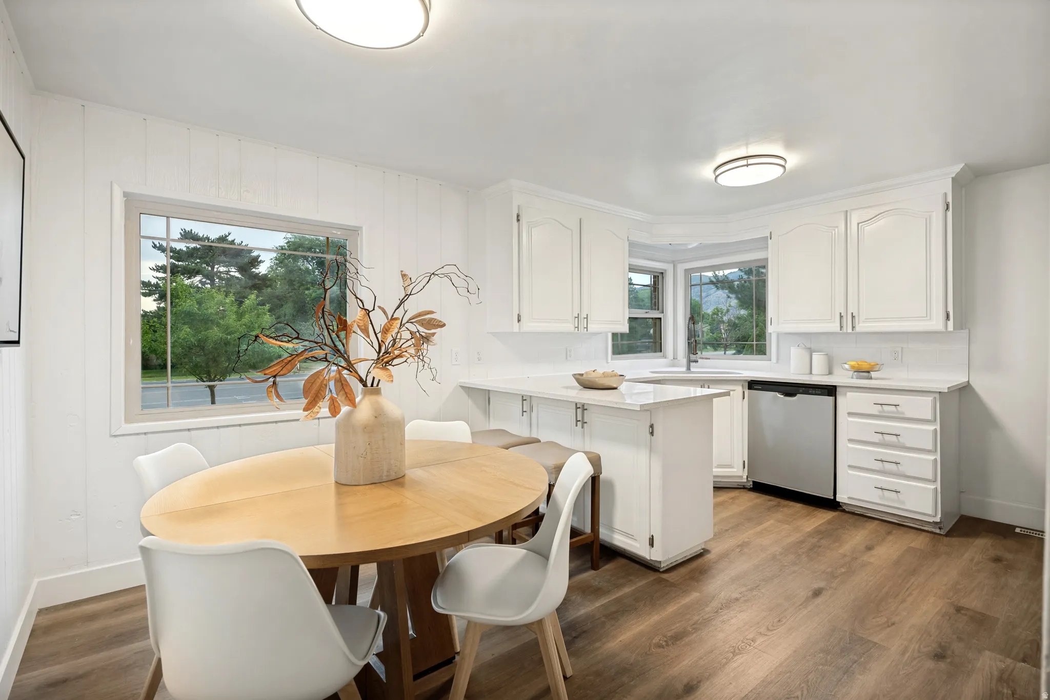 White cabinetry with chrome pulls, white countertops, and a stainless steel dishwasher
