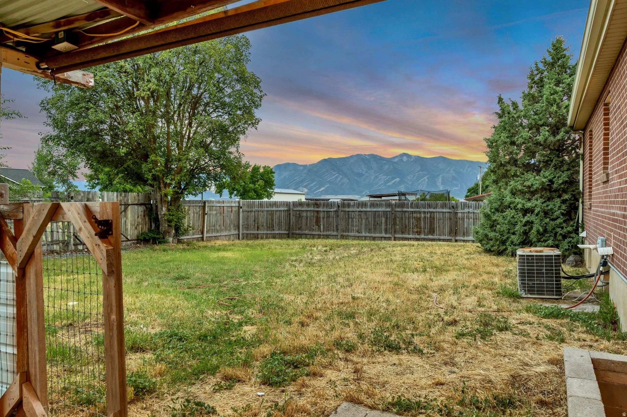 Expansive backyard featuring a wood fence, mature trees, and a mountain backdrop