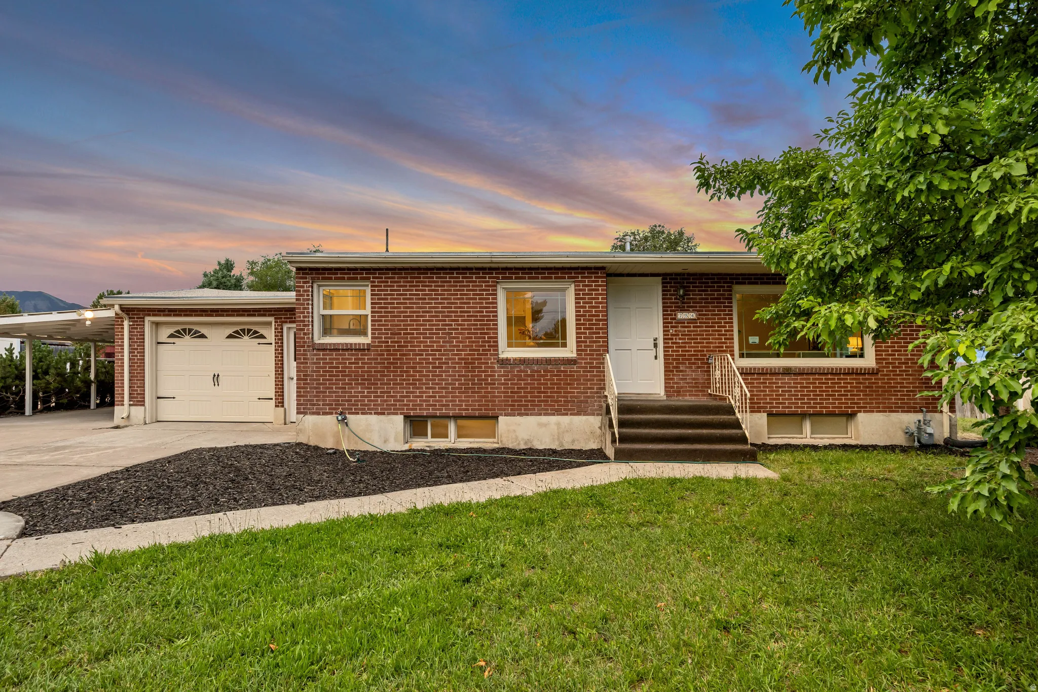 Brick exterior featuring a single-car garage and a covered carport
