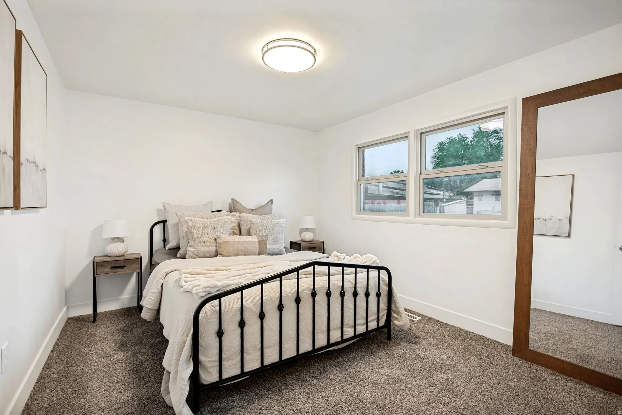 Bedroom featuring neutral carpeting, white walls, and two large windows