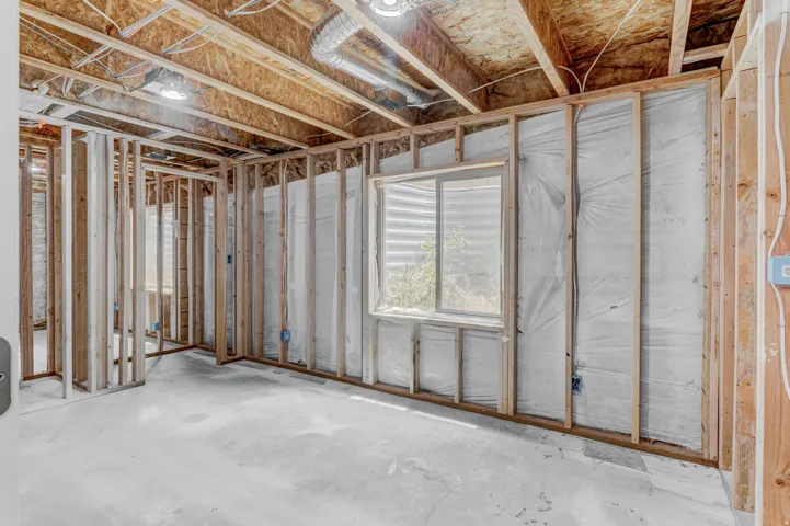Unfinished basement featuring exposed wood framing, concrete flooring, two windows, and visible ductwork