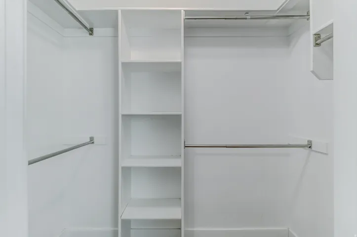 White custom closet system with multiple shelving units and chrome hanging rods