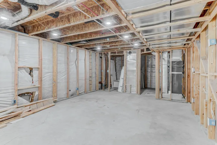 Unfinished basement space featuring visible wood framing, concrete flooring, and exposed ceiling joists