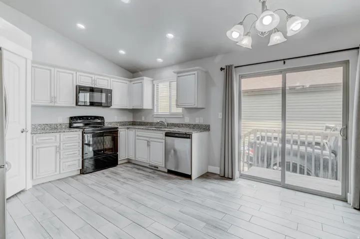 Kitchen featuring white cabinetry, granite-style countertops, wood-finish flooring, and a sliding glass door to exterior