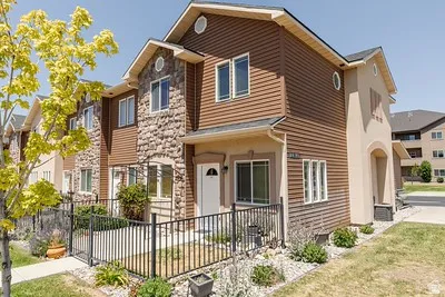 Multi-story residential exterior featuring a stone facade and horizontal siding