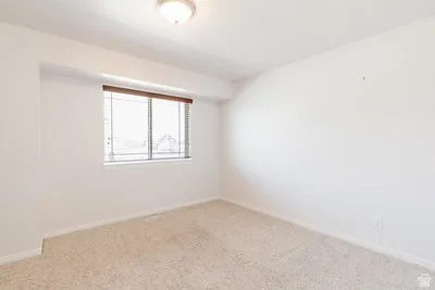 Carpeted room featuring a window with integrated blinds and a flush mount ceiling light