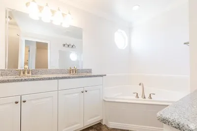 Bathroom featuring a double vanity with granite-style countertops, white cabinetry, and a large mirror