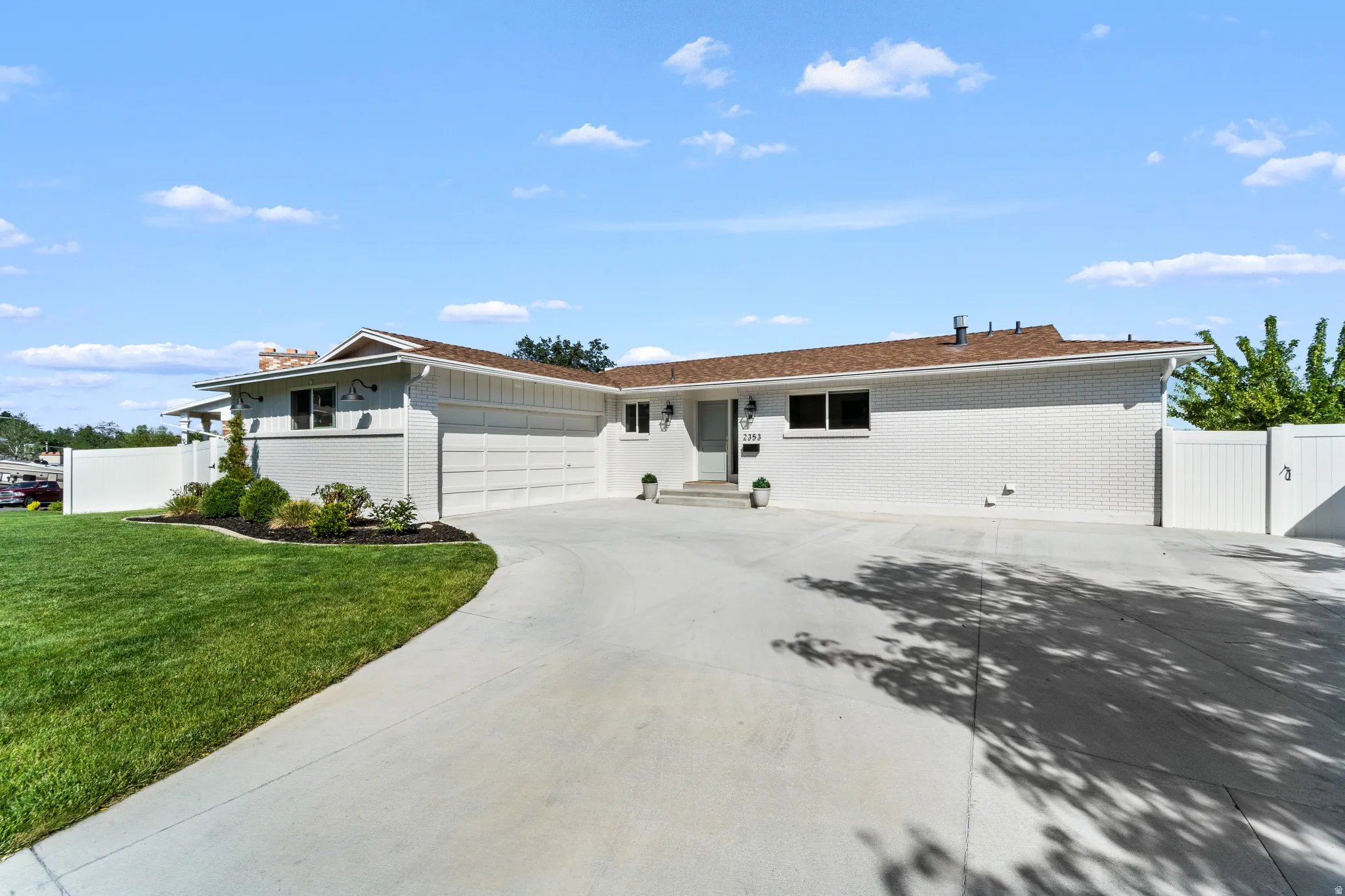 Exterior featuring white brick siding, a brown shingle roof, and a concrete driveway