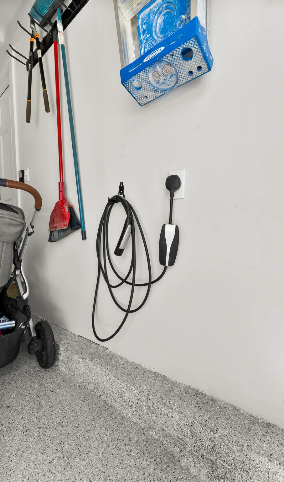 Garage space featuring an electric vehicle charging station, wall-mounted storage rack, and speckled epoxy flooring