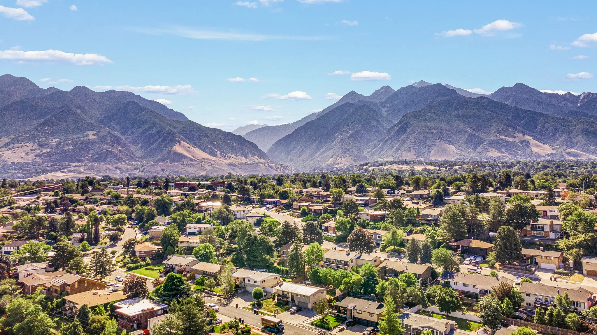 Expansive mountain backdrop framing a residential area with mature trees and varied architectural styles