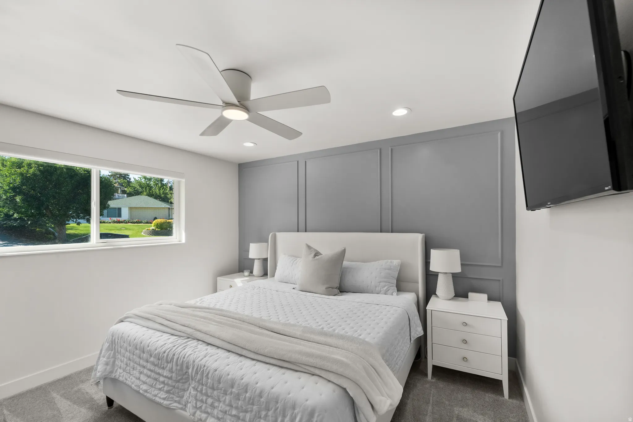 Recessed lighting and a modern ceiling fan illuminate this space, featuring a panel-accented wall