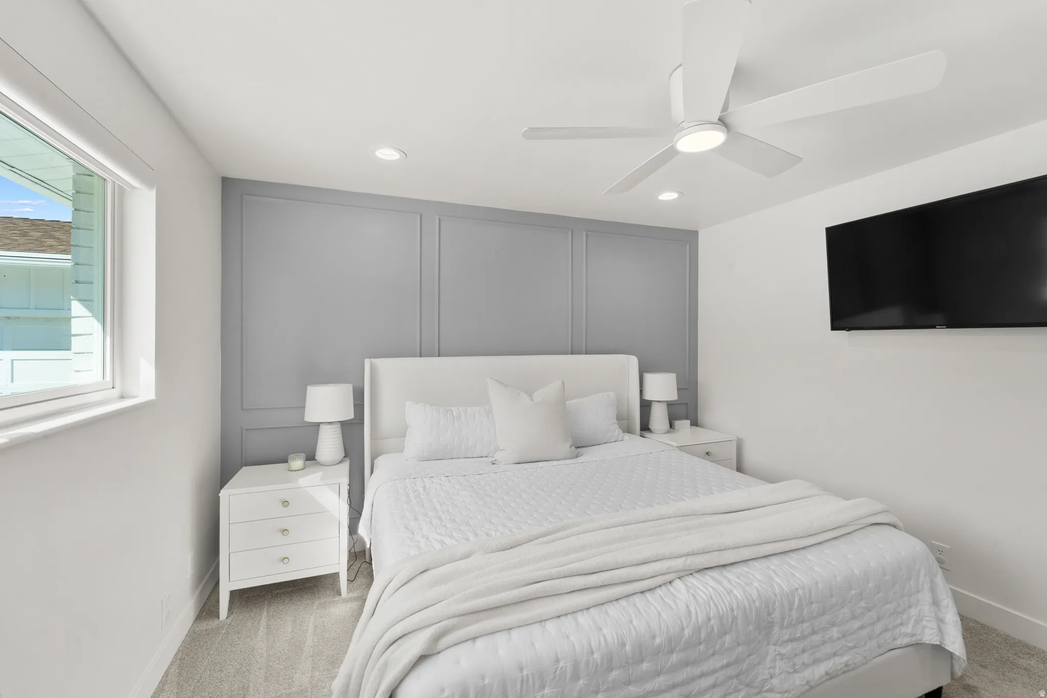Bedroom featuring a decorative accent wall with panel molding, carpet flooring, a ceiling fan with integrated lighting, recessed lighting, and a wall-mounted television