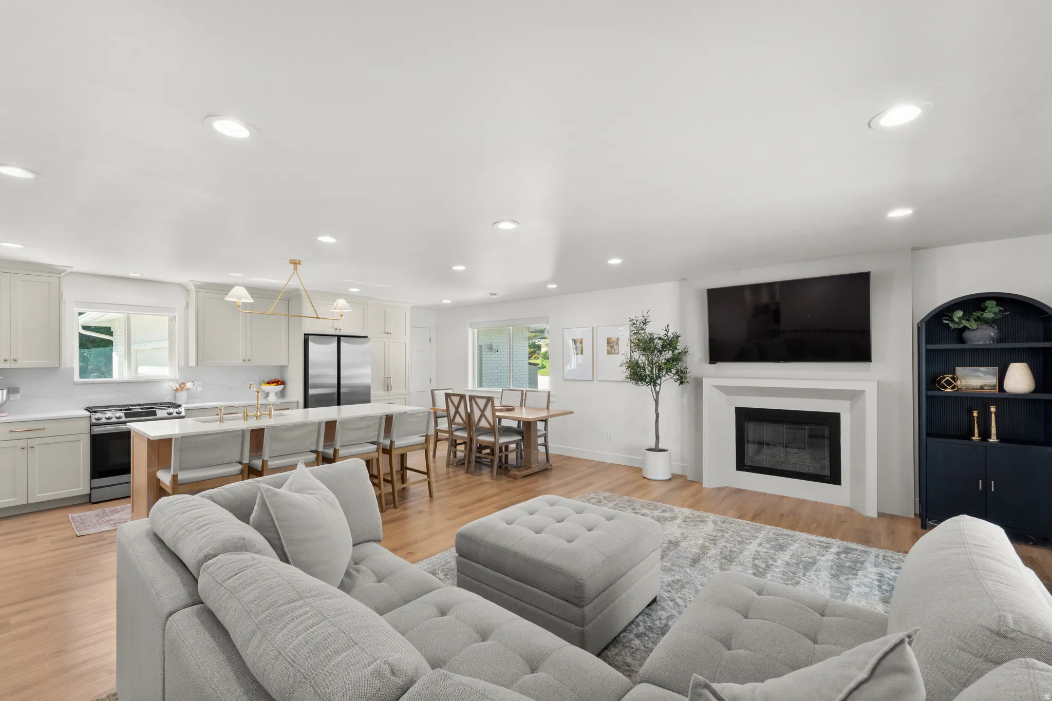 Open-concept living space with wood-finish flooring, recessed lighting, and a white fireplace