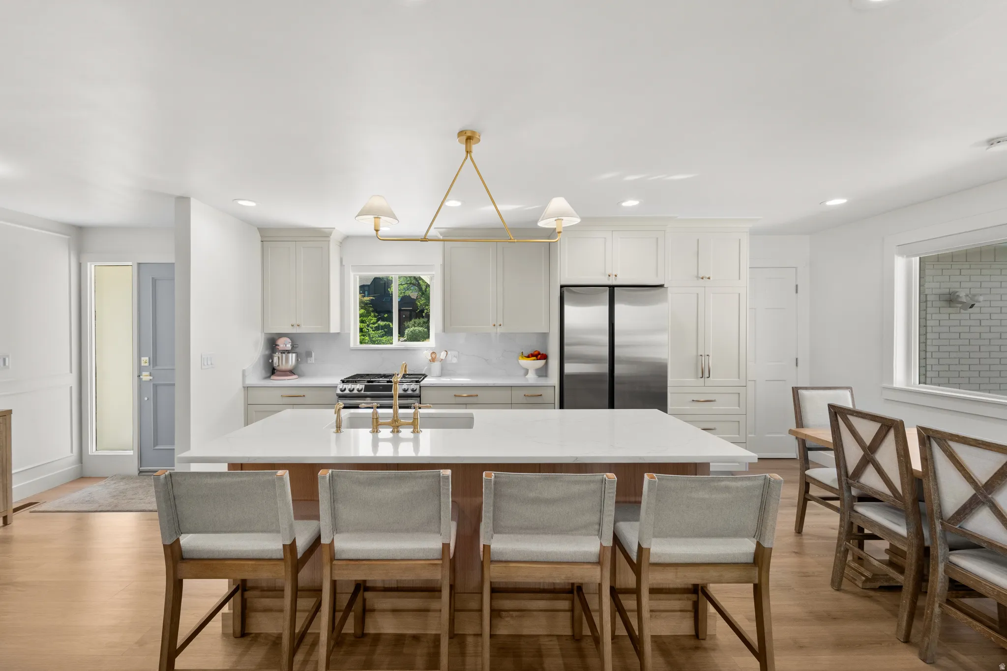 Open-concept kitchen featuring a large central island with seating, a stainless steel French door refrigerator, a gas range, and white shaker-style cabinetry