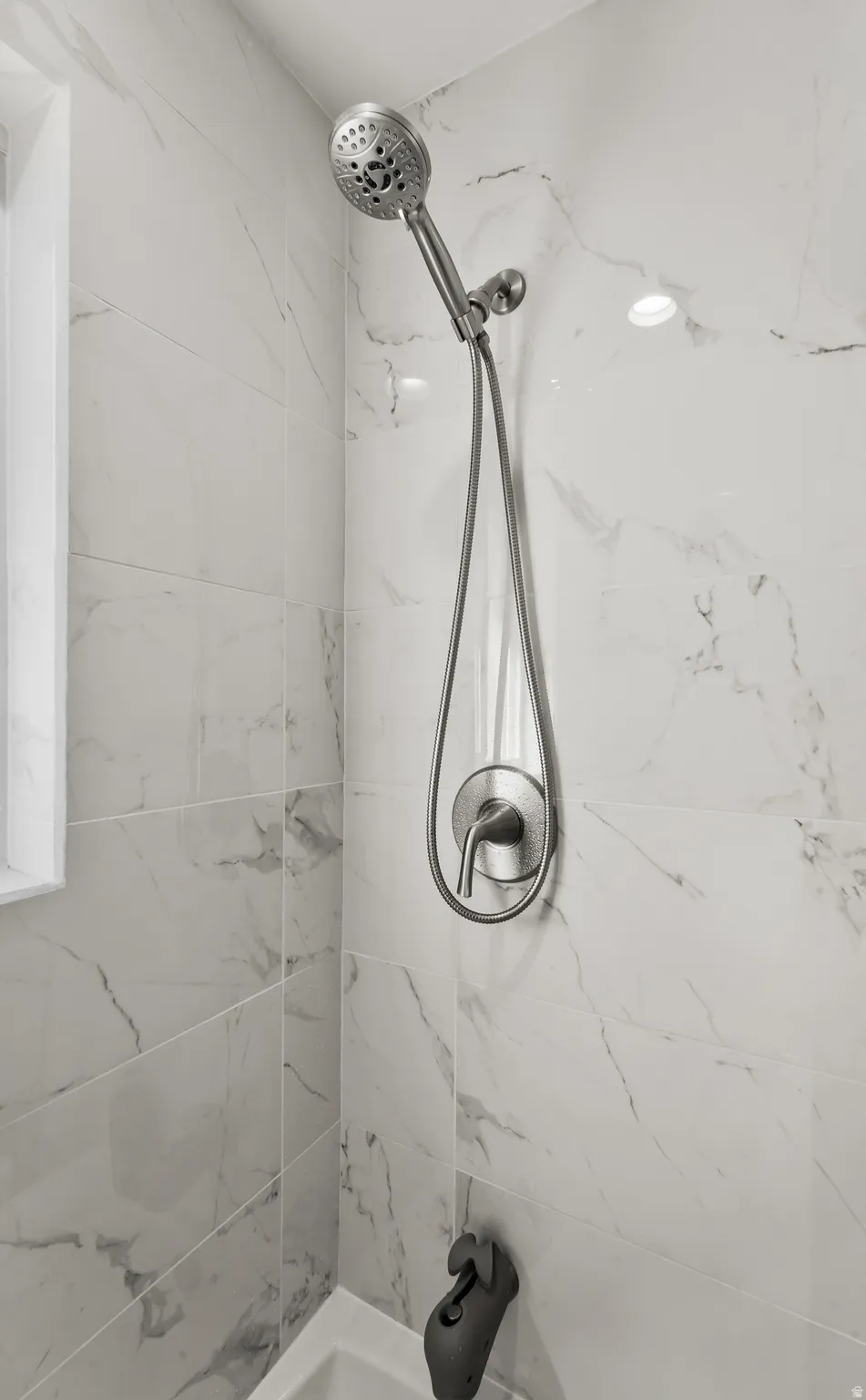 Contemporary shower with a handheld showerhead, single-handle control, and white marble-look wall tiling