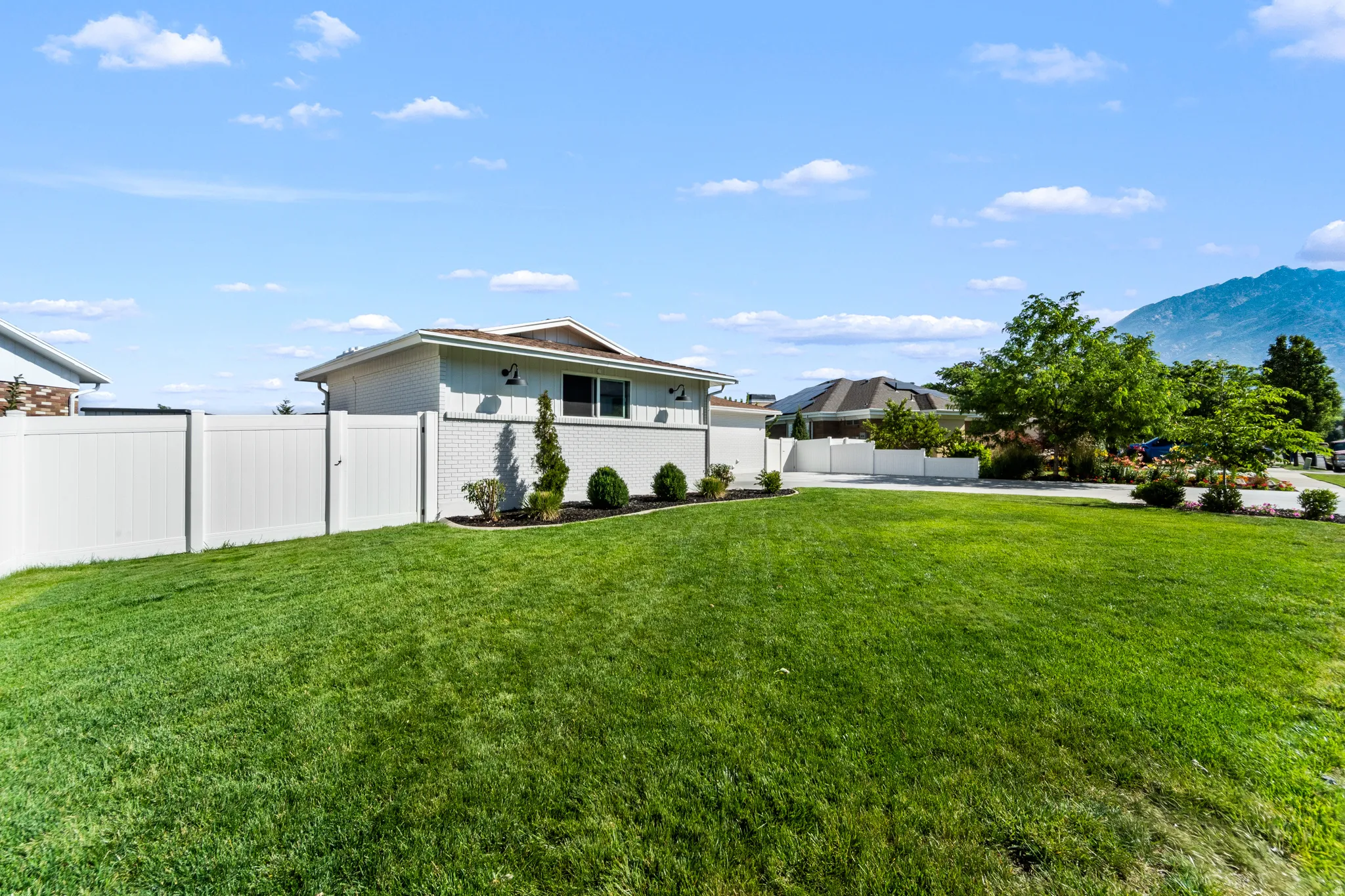 Expansive green lawn with a white vinyl privacy fence