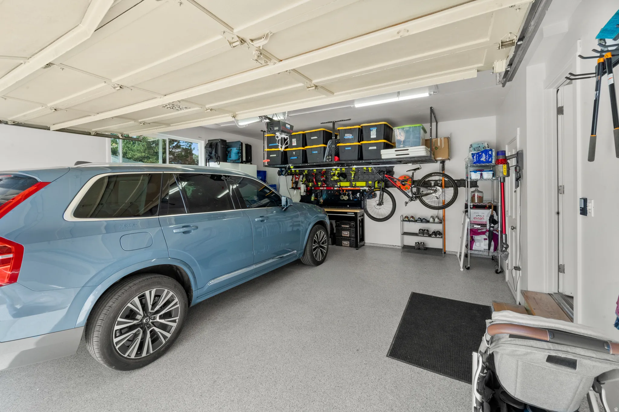 Epoxy-coated garage flooring, white painted walls, and overhead garage door with track system