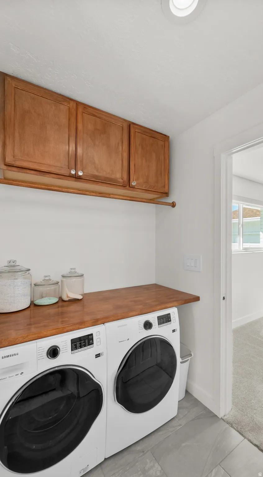 Laundry area featuring wood-finish cabinetry, a coordinating wood-finish countertop, and slate-style floor tiling