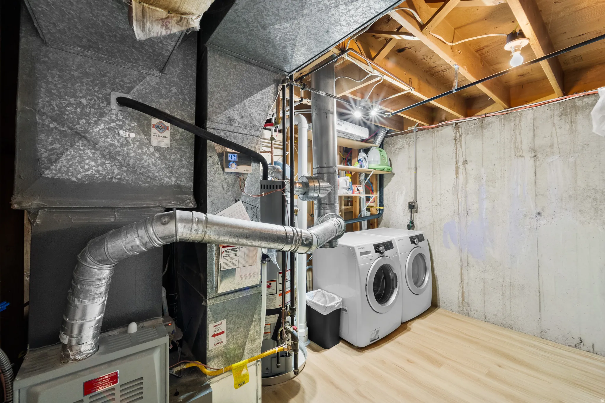Utility area featuring a furnace, water heater, and wood-finish flooring