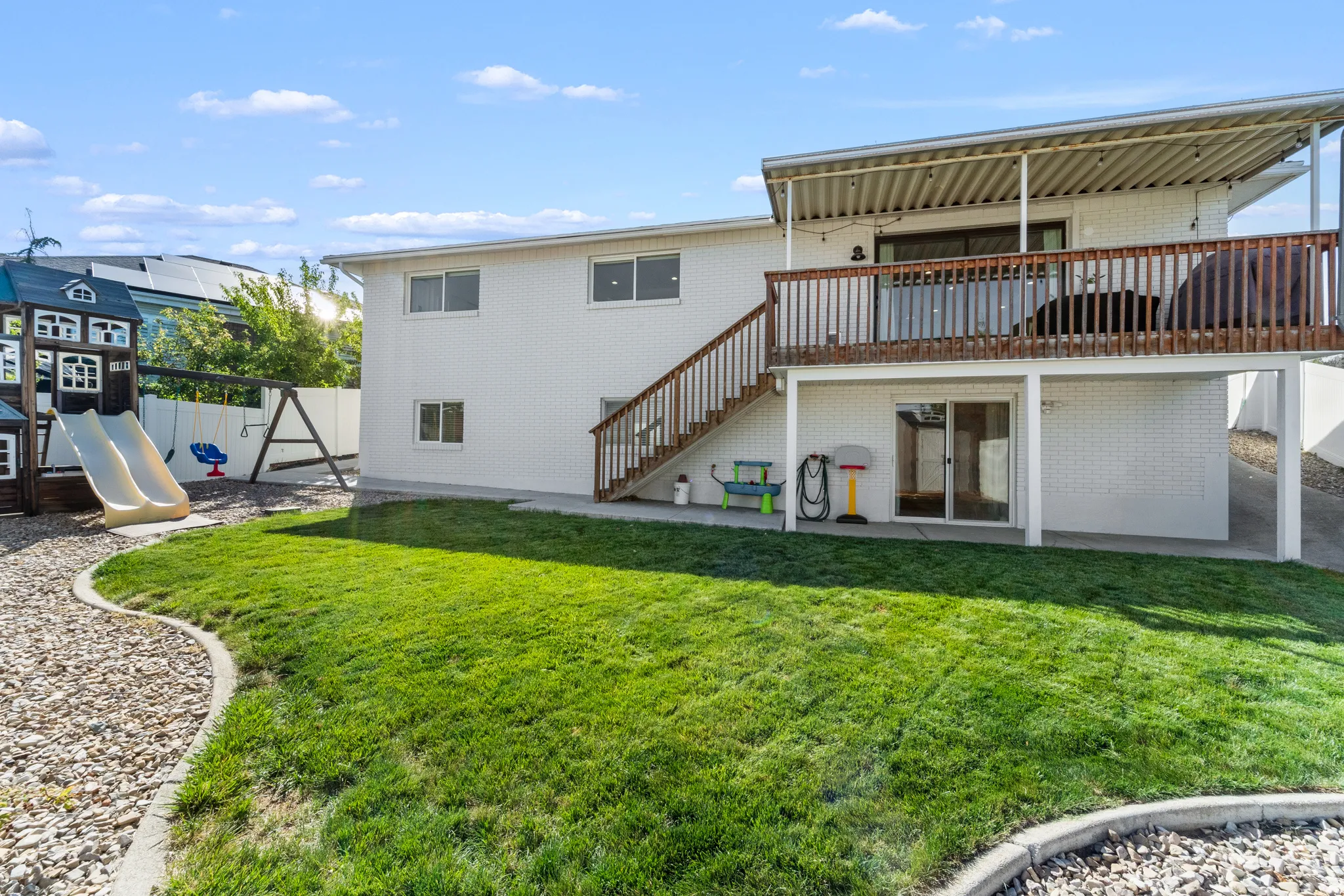 Expansive backyard featuring a manicured lawn, a gravel pathway with concrete edging, and a white privacy fence