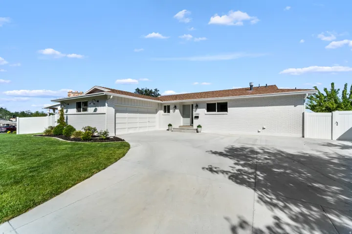Exterior featuring white brick siding, a brown shingle roof, and a concrete driveway