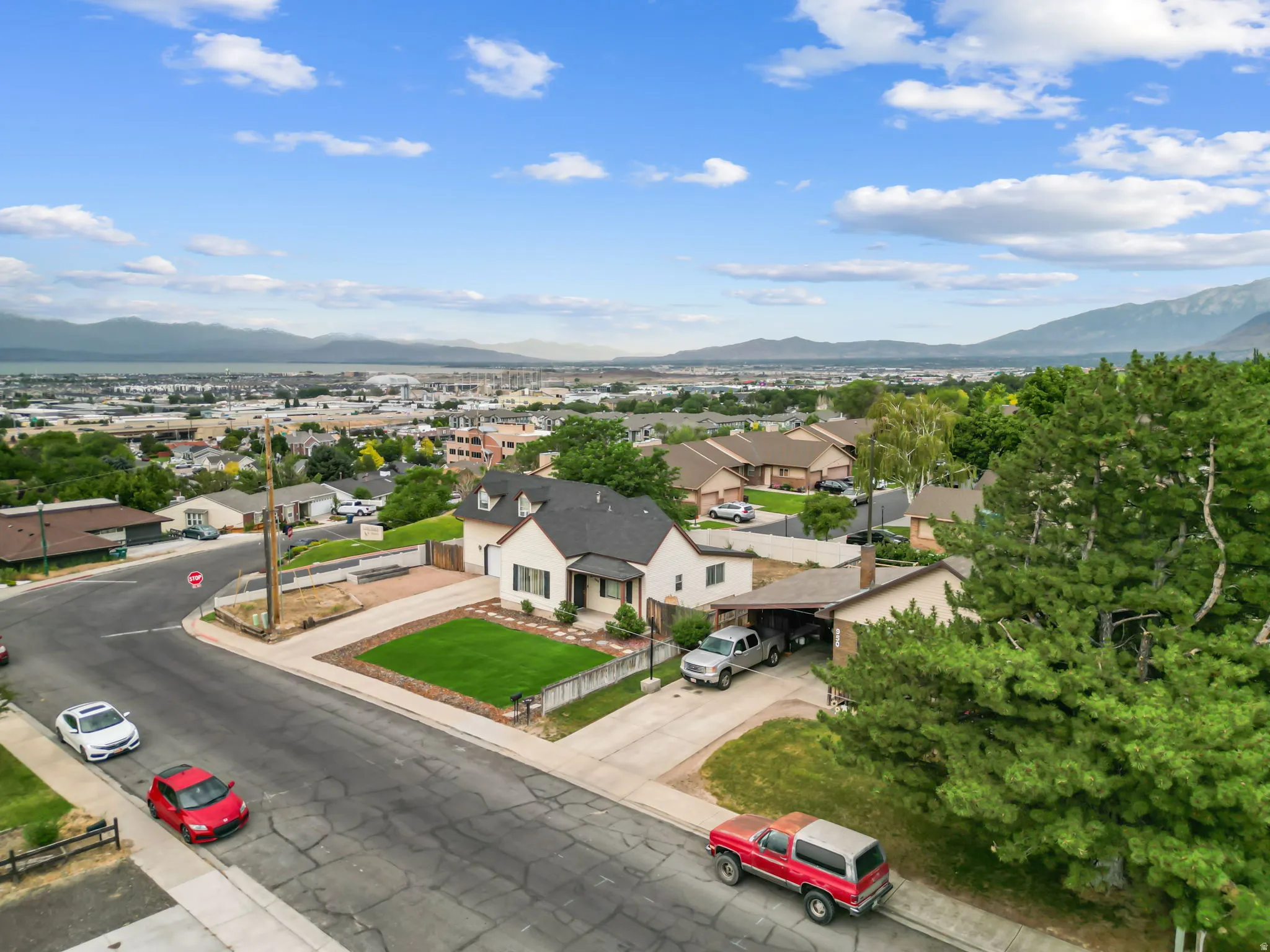 Elevated property featuring a light-toned exterior with dark roofing and a neatly maintained front lawn